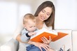 © BillionPhotos.com - Adult. Mother reading a book a little baby daughter on the sofa