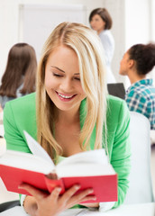 Canvas Print - smiling student girl reading book at school