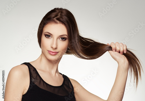 Naklejka - mata magnetyczna na lodówkę Young attractive brunette touching her healthy shiny hair.