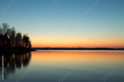 Foto Cabin on the point reflecting in the lake with spring sunset col