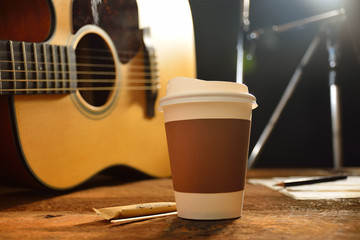 Wall Mural - Paper cup of coffee and guitar on wooden table