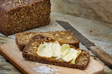 dark rye bread with seeds, butter and salt on rustic wood