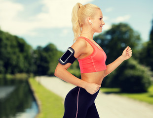 Canvas Print - sporty woman running with smartphone and earphones