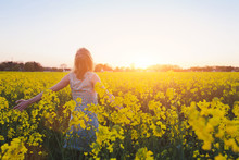 Happy Young Woman Enjoing Summer In Yellow Field At Sunset