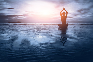 well being concept, beautiful sunset on the beach, woman practicing yoga