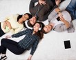 © Nejron Photo - Happy multiracial friends relaxing on a carpet with gadgets