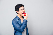 Young Asian Man Bitting Red Apple