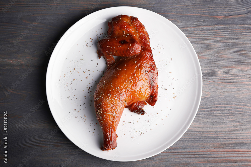 Smoked chicken leg on plate on wooden background