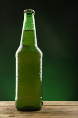 Wall Mural - Glass bottle of beer on dark green background