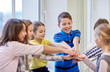 © Syda Productions - group of smiling school kids putting hands on top