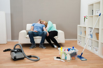 Exhausted Couple On Sofa In Living Room