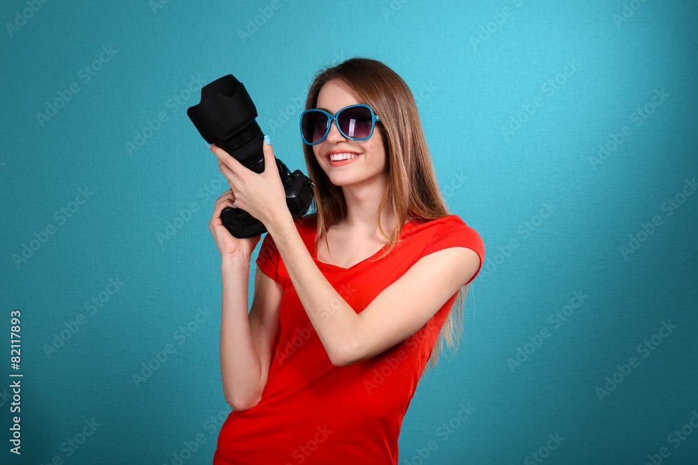 Young female photographer taking photos on blue background