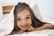 © Mike Kemp/Blend Images - Caucasian girl smiling under covers