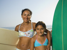 Hispanic Mother And Daughter Holding Surfboards