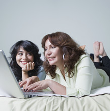 Young Woman And Mother Using Laptop On Bed