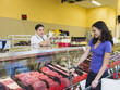 © Erik Isakson/Blend Images - Butcher serving customer at meat counter of grocery store