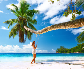 Wall Mural - Woman in blue dress swinging at beach