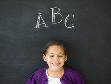 Hispanic Girl Standing Under 'ABC' On Chalkboard