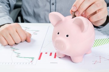 Wall Mural - Man putting coin in piggy bank. Saving money concept