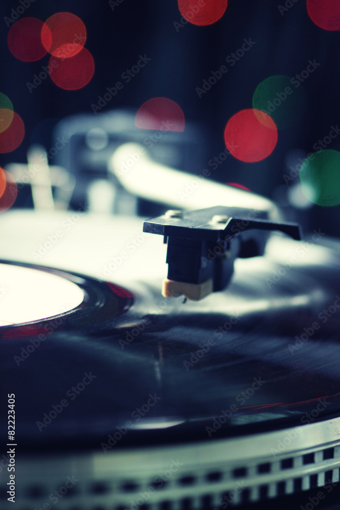 Gramophone with a vinyl record on colorful blurred background