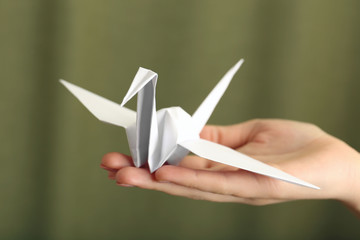 Poster - Female hand with paper crane on blurred background