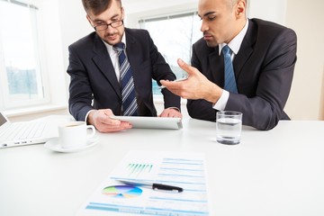 Wall Mural - Adult. Image of two young businessmen discussing document in