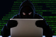 hacker in hood mask with computer hacking system in cybercrime