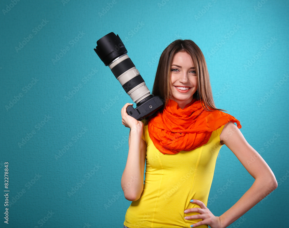 Young female photographer taking photos on blue background