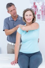 Wall Mural - Woman stretching her arm with her doctor