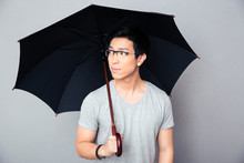 Asian Man Standing With Umbrella And Looking Away