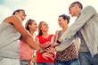 © Syda Productions - group of smiling friends with hands on top in city