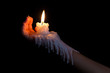 Open hand holding candle stick with wax flowing down the arm