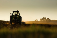 Tractor In Sunset Plowing The Field