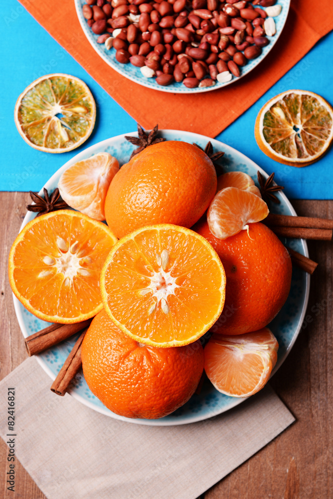 Orange tangerines, peanuts and cinnamon sticks on blue wooden table top view