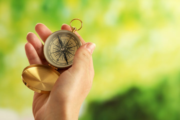 Female hand with compass on bright blurred background