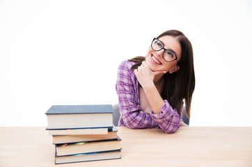 Poster - Happy thoughtful woman sitting at the table with books