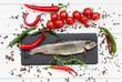 Trout fish on cutting board with cherry tomatoes