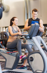 Canvas Print - happy woman with trainer on exercise bike in gym