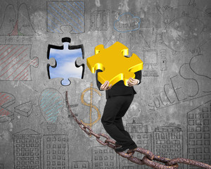 Businessman carrying gold jigsaw puzzle piece toward hole with s