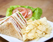 Turkey club sandwich and chips on a wooden table