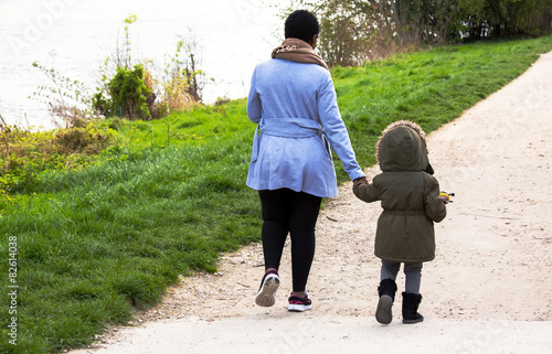 Fotografie, Obraz Mother holding a hand of her daughter in spring day outdoors