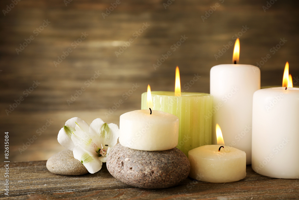 Beautiful composition with candles and spa stones on wooden background