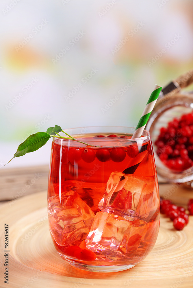 Compote with red currant in glass on wooden tray on light blurred background