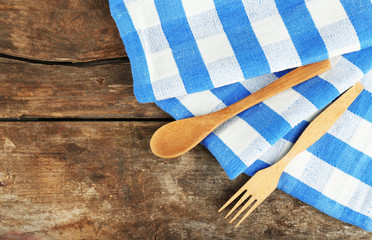 Checkered napkin with spoon and fork on wooden table background