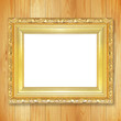 © peekeedee - Antique gold frame on wooden wall;. Empty picture frame on woode