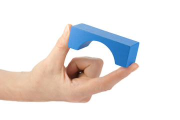 Blue wooden toy bridge in female fingers isolated