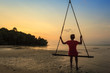 © Noppasinw - woman sit on swing bar look at sunset at the beach