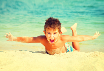 Wall Mural - Summer holidays. Joyful boy having fun at the beach