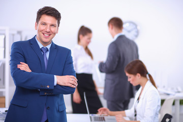 Wall Mural - Successful business man standing with his staff in background at