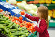 © MNStudio - Little girl choosing tomatoes in a food store